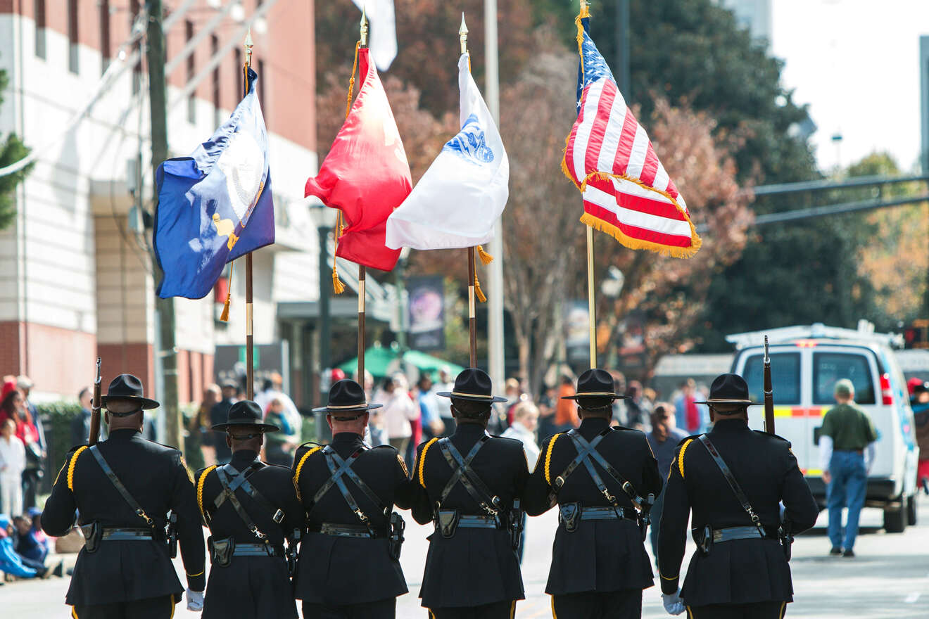 Honor guard in uniform carrying flags in a parade, with a focus on the ceremonial aspect and the significance of the occasion