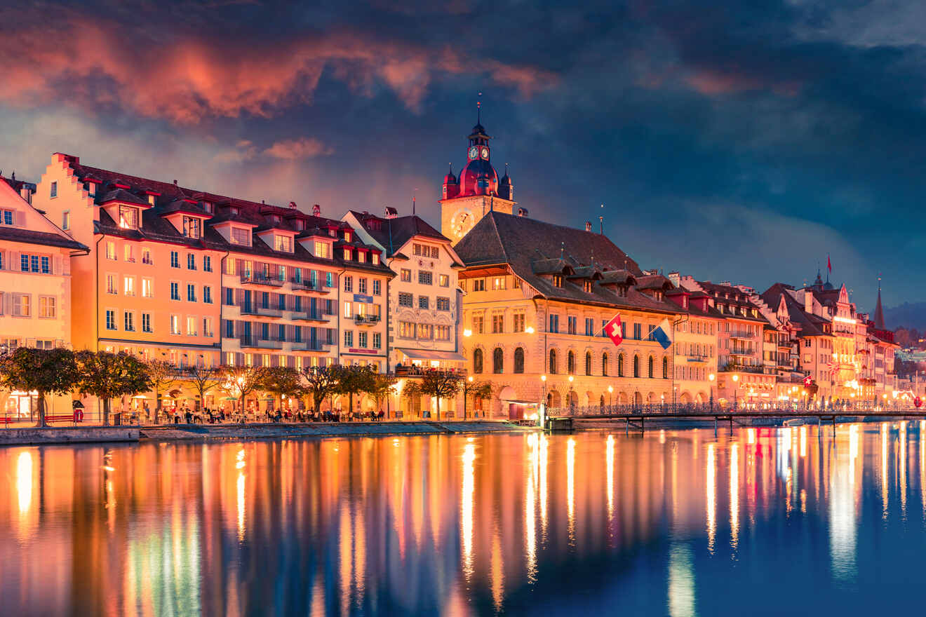 Twilight scene of Lucerne's historic architecture reflected in the calm waters of the Reuss River, with the illuminated tower of the Town Hall rising prominently