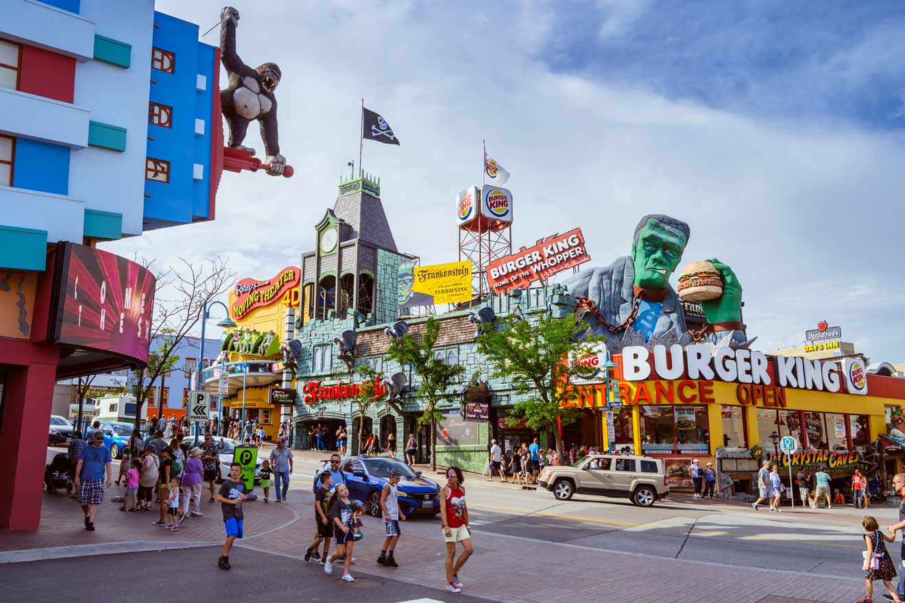 Colorful street view in Niagara Falls with themed restaurants and attractions, including a towering Frankenstein holding a burger.