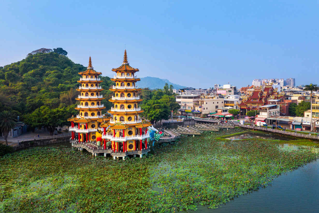 Aerial view of the Dragon and Tiger Pagodas in Kaohsiung, Taiwan, situated on a lotus-filled lake with surrounding greenery and urban buildings.