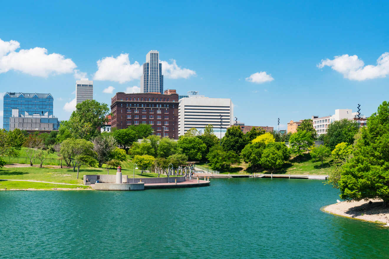 A cityscape view of Omaha featuring a park with a pond and various buildings in the background