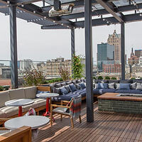 Chic rooftop lounge area with plush seating and panoramic city views in the backdrop