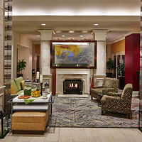 A cozy hotel lobby featuring a fireplace, armchairs, and a table with refreshments.