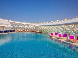 Luxurious rooftop pool with a white structural canopy and vibrant pink loungers.