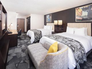 Double room in a hotel featuring two queen beds with chic bedding and abstract wall art