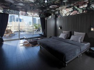Luxurious bedroom with dark floral ceiling design and a large bed, offering a city view