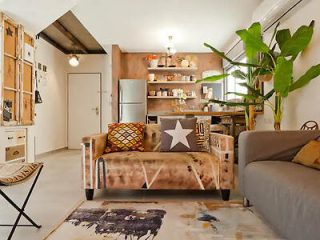 A bright, artistic open-plan living space with eclectic furniture and a creative, cozy ambiance.