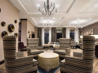 Modern hotel lobby with artistic stacks of cushioned seats, contemporary lighting, a round central table, and wall art