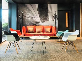 Chic hotel lobby with a statement red couch, stylish mid-century modern chairs, and large-scale black-and-white photography