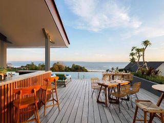 A serene outdoor dining setting on a wooden deck with a panoramic view of the ocean