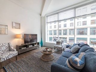 Cozy urban living room with a large blue sectional sofa, patterned rug, and street view through large windows