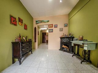 A hallway with green and beige walls, decorated with art and vintage furniture.