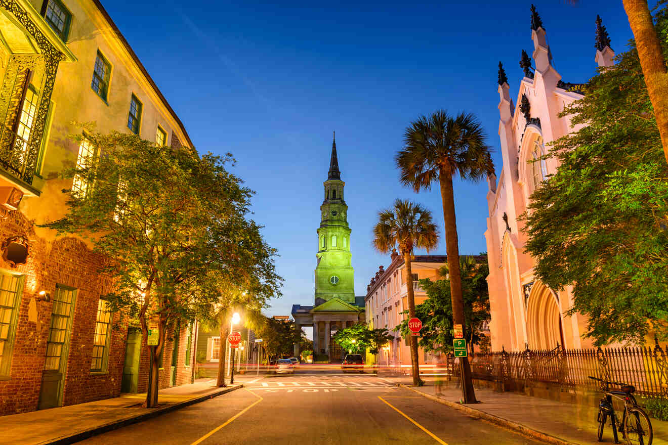 Nighttime scene of a quiet street in Charleston, with the lit steeple of St. Philip's Church rising majestically against the evening sky, flanked by palm trees and historic architecture.