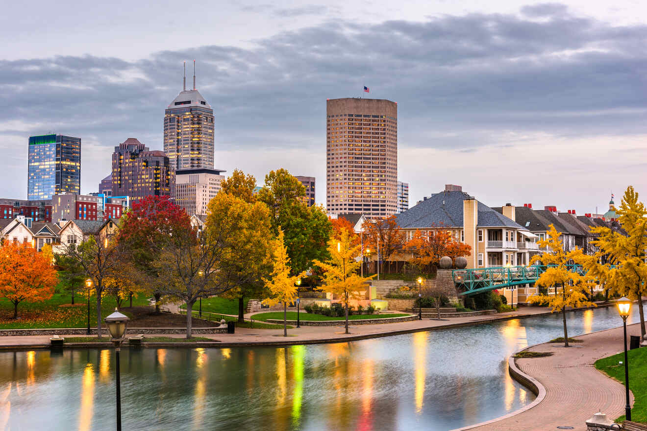 Autumn in Indianapolis with trees in vibrant fall colors, reflecting in the canal, against a backdrop of the city's skyline during twilight