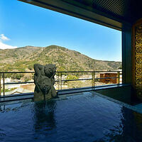 An onsen bath with a view, featuring a sculpture and a panoramic window overlooking a mountainous landscape