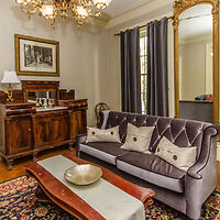 Elegant traditional living room with a purple tufted sofa, ornate wooden furniture, and classic decor