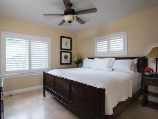 A tranquil bedroom with a large bed, white linens, a ceiling fan above, and a tasteful decor