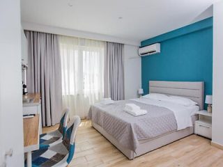 Contemporary hotel room with a blue accent wall, large bed, and seating area by a wide window.