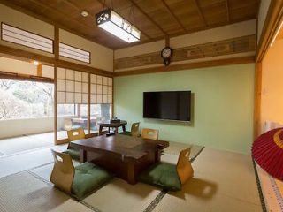 Traditional Japanese-style room with tatami floors, a low wooden table, floor cushions, and a mounted flat-screen TV