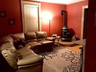 Homely living room with a large leather sofa, warm lighting, and a wood-burning stove for a comfortable atmosphere.