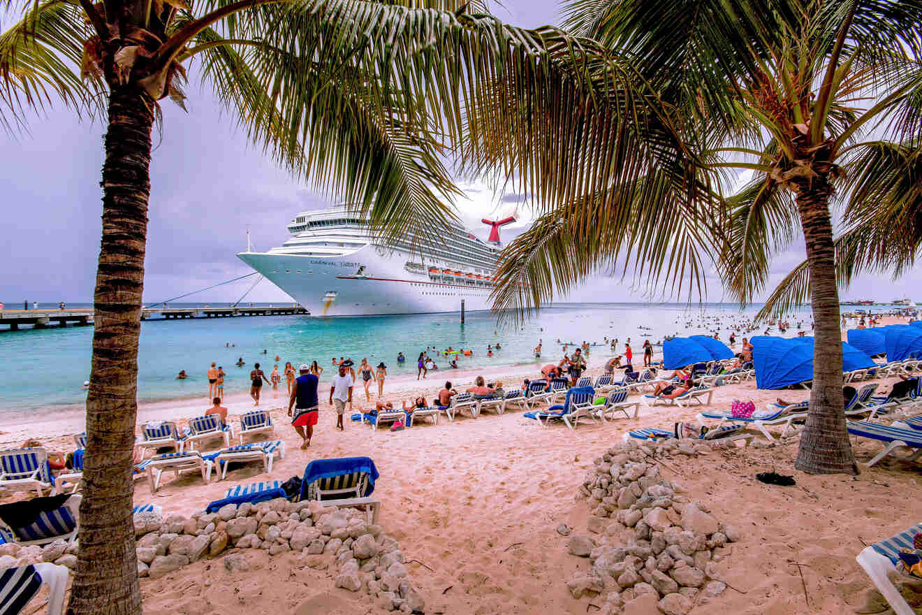 A bustling beach scene with a cruise ship docked near the shore, palm trees, and people enjoying the sandy beach and clear blue waters.