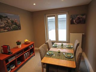 Dining area in a homely apartment, set with a table for four and a kitchen shelf stocked with essentials