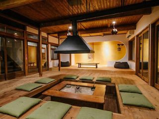 Traditional Japanese dining room with sunken seating, green cushions, and a central charcoal grill