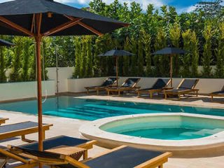 Secluded hotel pool area with sun loungers, umbrellas, and lush greenery providing privacy.