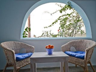 Inviting outdoor seating area with wicker chairs and a white table set against an arched window with a view of greenery.