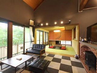 Eclectic living room with black leather seating, checkered floor, traditional Japanese alcove, and a wood stove