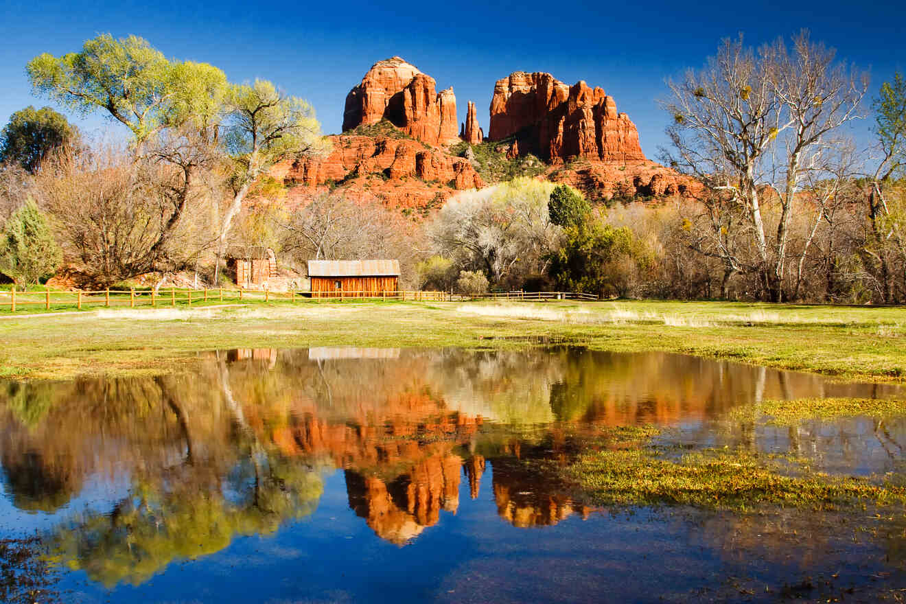 Reflection of Cathedral Rock in Sedona mirrored in a tranquil pond surrounded by greenery and a rustic wooden barn
