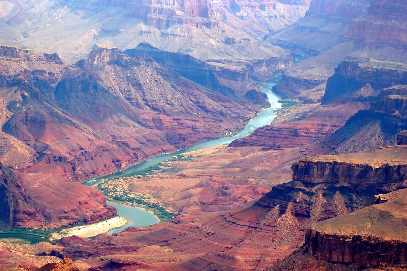 Aerial view of the Grand Canyon showcasing the winding Colorado River, with sunlit ridges and deep, shadowed canyons.