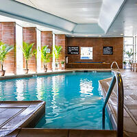 An indoor hotel pool area surrounded by brick walls and large windows