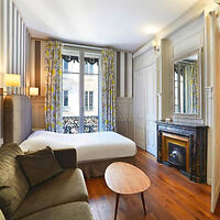 Cozy hotel room with a double bed, fireplace, and large windows with curtains, blending modern and classic elements