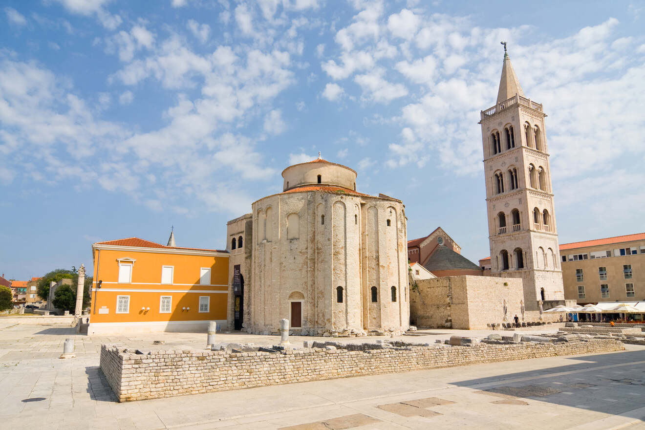 The Byzantine St. Donatus Church in the Old Town, A historic site featuring a circular stone church and a tall bell tower against a partly cloudy sky