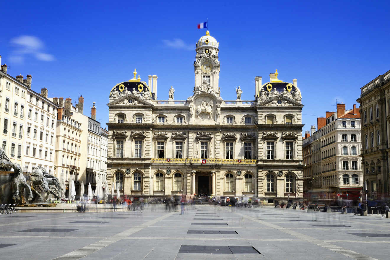 The historic Lyon City Hall (Hôtel de Ville) facing a spacious public square, with its classical architecture and ornate clock tower under a clear blue sky