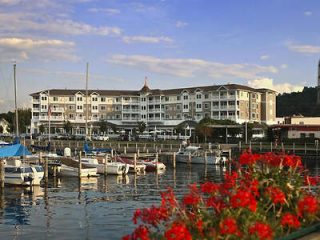 A waterfront view of a large multi-story hotel with boats moored at a marina in the foreground and vibrant red flowers