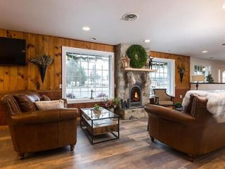 A spacious and inviting lodge interior with plush leather sofas, a large fireplace, and rustic wooden decor