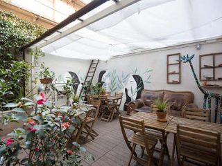 A quaint rooftop garden café decorated with artistic wall murals and greenery, providing a cozy urban retreat.