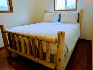 A rustic wooden bed frame with clean white bedding in a room with natural light