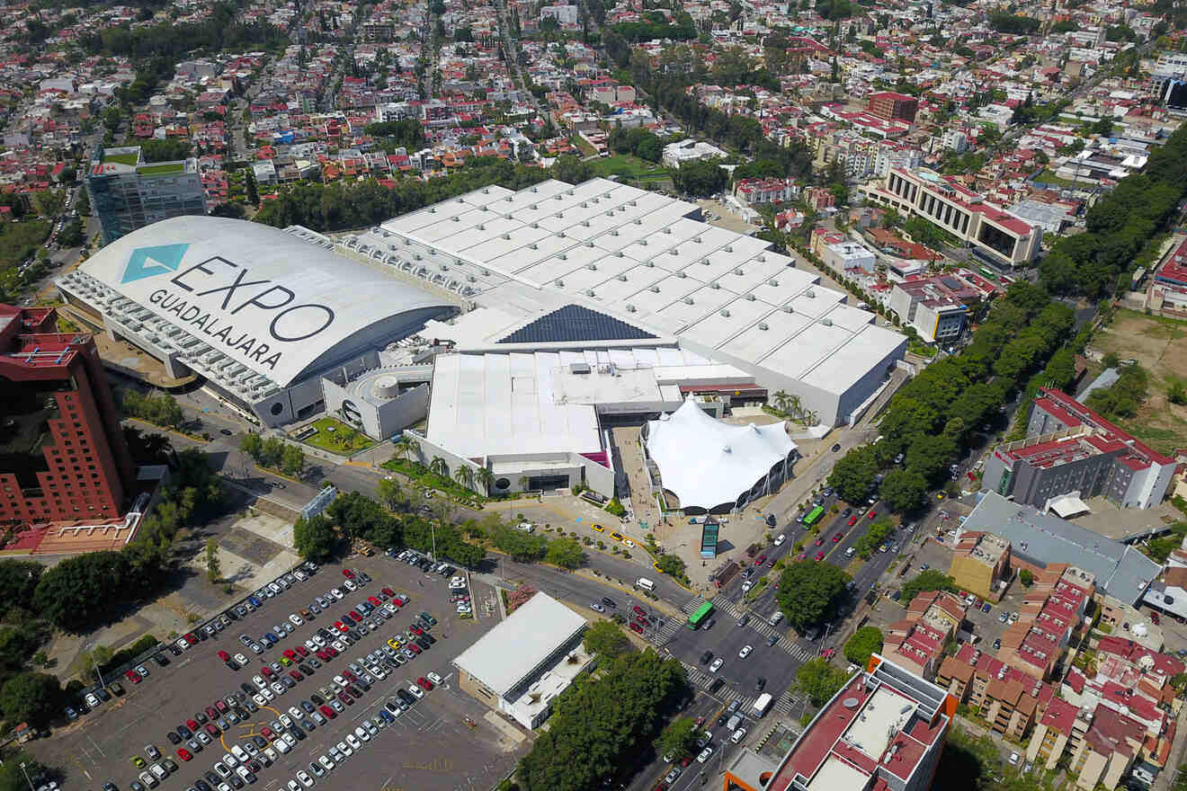 Aerial view of Expo Guadalajara with its distinctive white roofing, surrounded by parking lots and the dense urban landscape