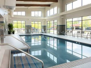 An indoor hotel swimming pool with large windows and a spacious seating area