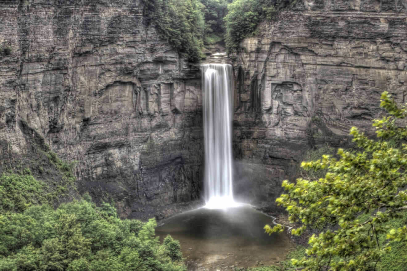 The grandeur of Taughannock Falls State Park is captured in a photograph showcasing the towering waterfall surrounded by rocky cliffs and lush greenery