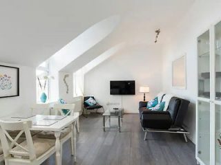 Modern living room with white furniture, grey floors, and pops of turquoise decor accents