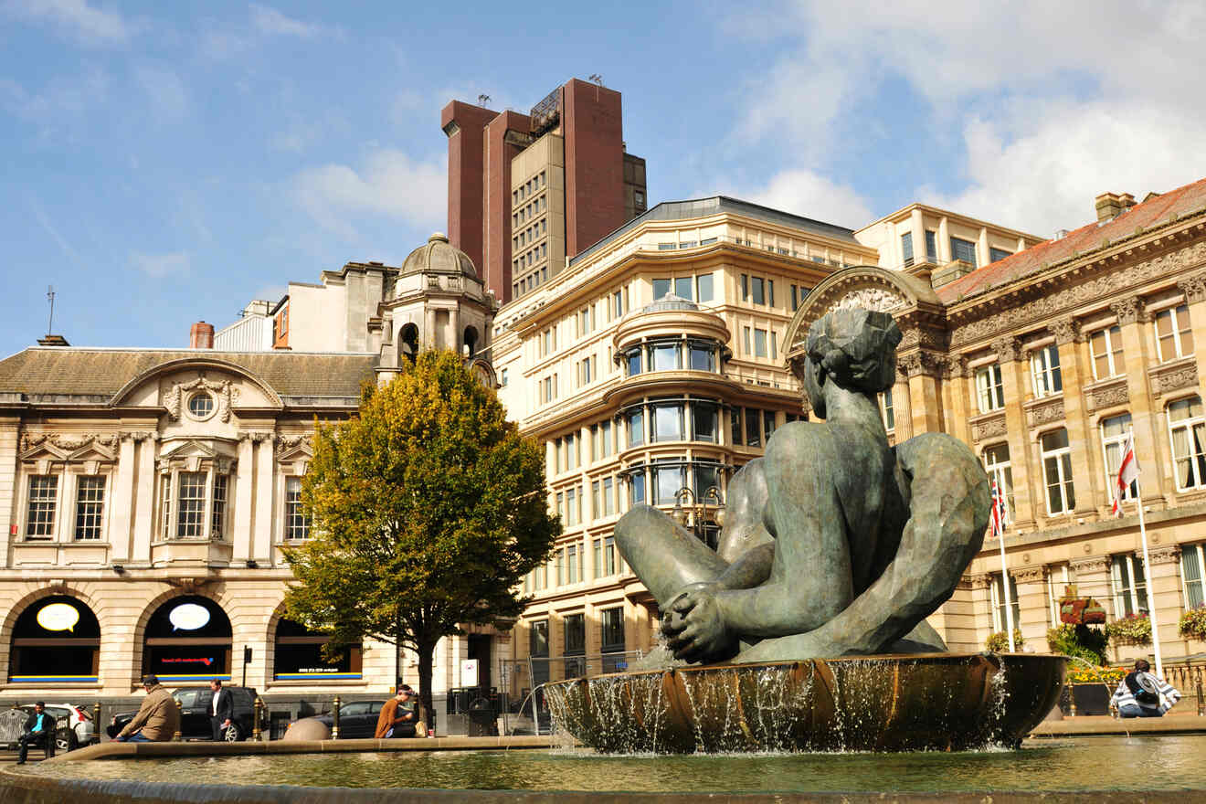 Classical fountain statue in an urban square, with grand historical buildings and a mix of modern and traditional architecture in the background