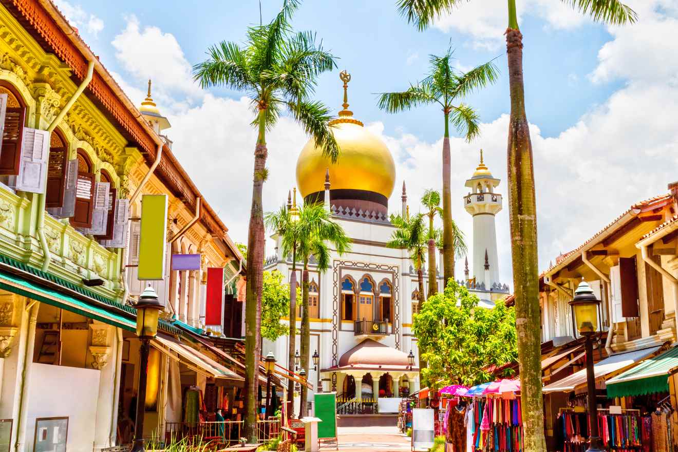 A street in singapore with palm trees and a mosque.