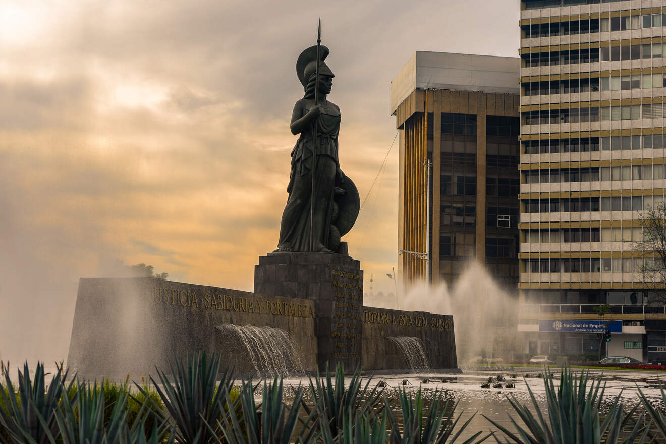 Monument to Minerva, the Roman goddess, at a roundabout in Guadalajara, with a fountain at its base and inscriptions of 'Justice, Wisdom, and Strength' in Spanish