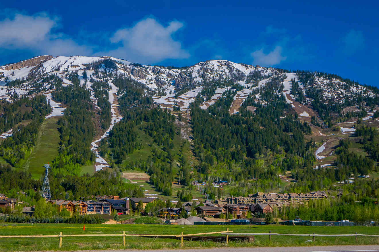 A view of houses below a mountain in summer, where to stay in Jackson Hole