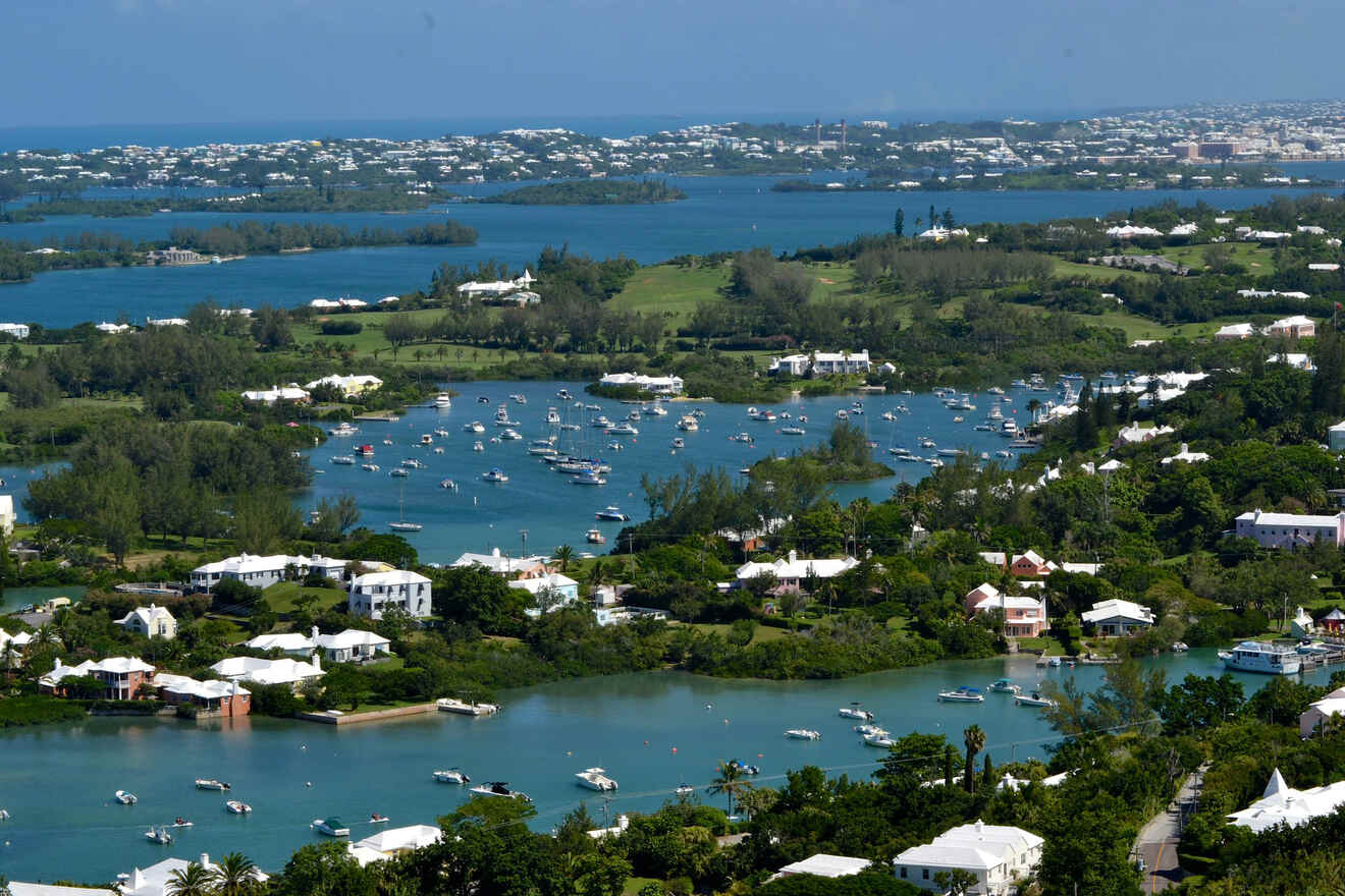 Aerial view of a coastal area with numerous boats docked in the water, surrounded by green landscapes and residential buildings.