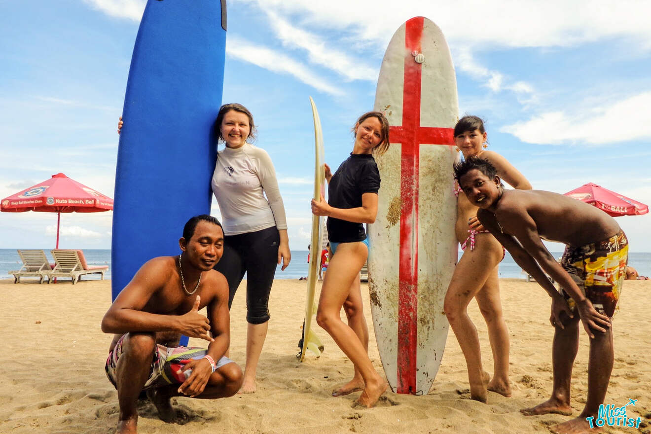 A group of people posing with surfboards on the beach.